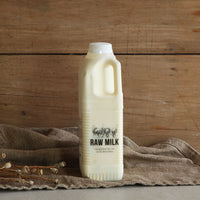 Fen Farm Dairy 1L raw milk bottle of unpasteurised Montbliarde milk on rustic wooden background