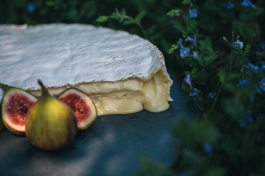 A picture of our delicious Baron Bigod brie, oozing on a slate with some figs
